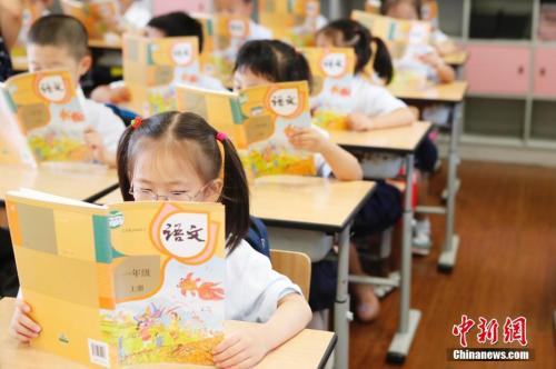 资料图：孩子们正在认真阅读《语文》教材。 殷立勤 摄