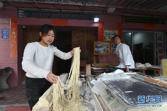 1月3日，在福建省南安市蓬华镇蓬岛村，郭炜兰（左）帮助哥哥郭炜龙（后）制作手工面。新华社记者 宋为伟 摄