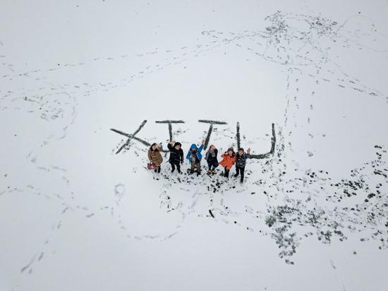 1月3日，西安交通大学学生在雪地里“绘出”校名英文缩写“XJTU”字样，李斌摄。