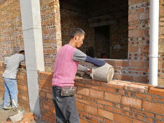 右臂残缺的建筑农民工胡元清正在砌砖。网友“永州号外” 摄