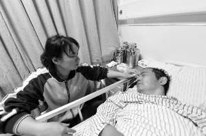 胡先生目前住在脑科医院病房，已脱离生命危险，妻子在一旁照顾他