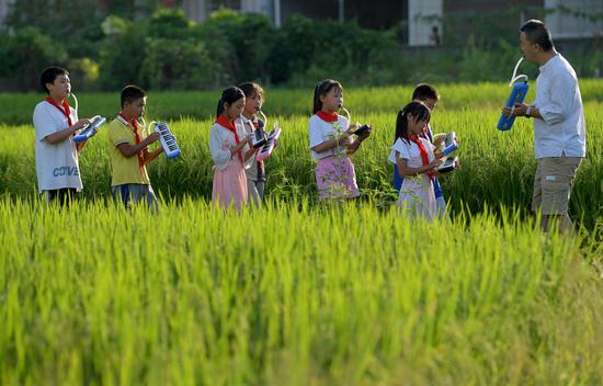 Yang Hao (1st R) holds a weekly field training session for members of Yantian Primary School's melodica band in Gaocun Township, Wanzai County, east China's Jiangxi Province, Sept. 3, 2020. (Xinhua/Peng Zhaozhi)