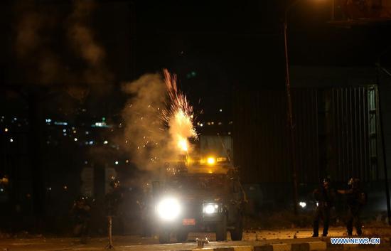 An Israeli military vehicle fires tear gas canisters at Palestinian protesters at Huwwara checkpoint near the West Bank city of Nablus, on May 10, 2021. Tension between Israelis and Palestinians has been flaring up over the past few days amid the escalating violence in East Jerusalem between Palestinian demonstrators and Israeli forces. (Photo by Ayman Nobani/Xinhua)