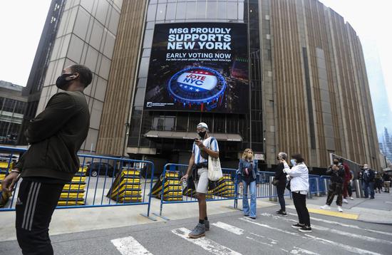 Wearing masks, voters line up with social distance to vote during the in-person early voting outside a polling station in Madison Square Garden in New York, the United States, Oct. 24, 2020. Early voting began across New York State on Saturday, offering voters nine days to cast their ballots prior to Election Day. (Xinhua/Wang Ying)