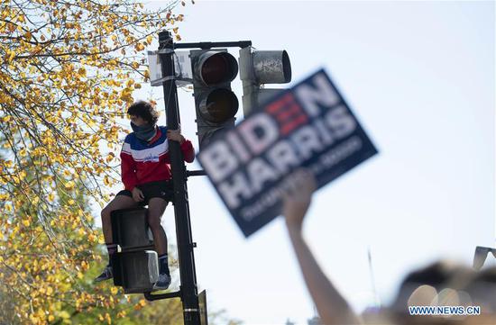 A man sits on a traffic light near the White House in Washington, D.C., the United States, on Nov. 7, 2020. U.S. Democratic presidential nominee Joe Biden was projected Saturday by multiple U.S. media outlets to be the winner of the 2020 election. Sitting President Donald Trump said the election is "far from over," vowing to take legal actions. (Xinhua/Liu Jie)