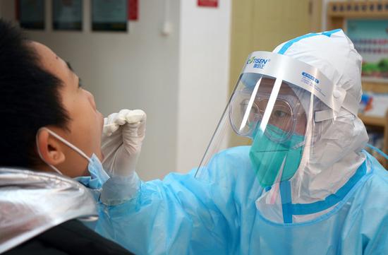 A medical worker collects a swab sample from a resident at a community COVID-19 testing site in Yuhua District of Shijiazhuang, capital of north China's Hebei Province, Jan. 12, 2021. (Xinhua/Jin Haoyuan)