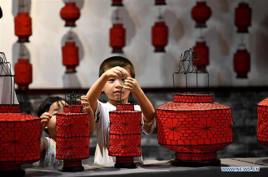 Children view handmade lanterns in a cultural industry zone in Qiaoxi District of Shijiazhuang City, north China's Hebei Province, Aug. 10, 2020. Qiaoxi has organized a series of activities to enrich children's summer vacation and promote the intangible cultural heritages. (Photo by Xu Jianyuan/Xinhua)