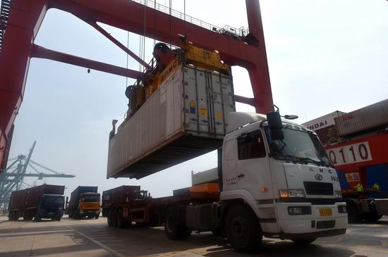 A crane loads a container onto a truck at Tianjin port container terminal in Tianjin, east China, Aug. 4, 2020. (Photo by Zhao Zishuo/Xinhua)