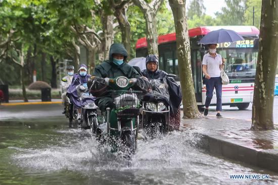 People ride past a flooded road in east China's Shanghai, Aug. 5, 2020. Hagupit, the fourth typhoon of this year, has brought heavy downpours to Shanghai since Tuesday, causing urban waterlogging in some areas and disrupting traffic, according to the municipal flood control department. (Xinhua/Wang Xiang)