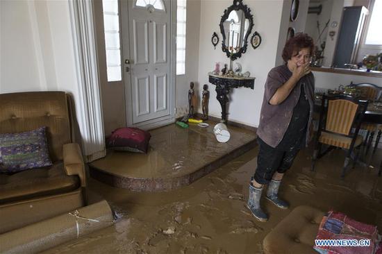 A woman reacts in her flooded house after a heavy storm in Bourtzi, Evia island, Greece, on Aug. 9, 2020. The death toll from the extreme weather phenomena which swept through Evia island in central Greece on Sunday climbed to seven with two more people were found dead, according to the latest announcement by local authorities. (Xinhua/Marios Lolos)