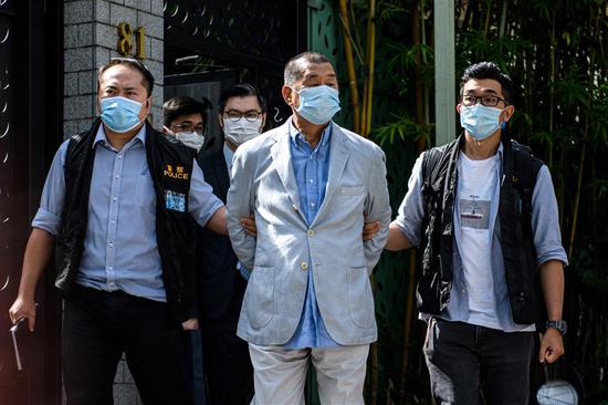 Police take away the owner of Apple Daily Jimmy Lai (center), 71, from his residence after he was arrested under the new national security law in Hong Kong on Monday.