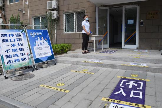 A staff member is on duty at the entrance of a dormitory in Beijing University of Chemical Technology in Beijing, capital of China, May 27, 2020. (Xinhua/Ju Huanzong)