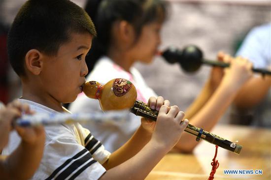 Children play the cucurbit flute in a cultural industry zone in Qiaoxi District of Shijiazhuang City, north China's Hebei Province, Aug. 10, 2020. Qiaoxi has organized a series of activities to enrich children's summer vacation and promote the intangible cultural heritages. (Photo by Xu Jianyuan/Xinhua)
