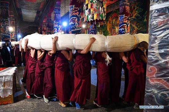 Buddhist monks carry a huge Thangka painting at the Drepung Monastery in Lhasa, southwest China's Tibet Autonomous Region, Aug. 19, 2020. Celebrations for the traditional Shoton Festival, or Yogurt Festival, began in Lhasa on Wednesday. (Xinhua/Zhan Yan)