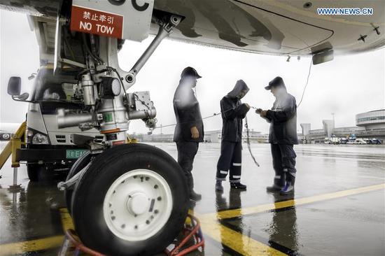 Ground crew members conduct pre-flight check on a passenger plane amid a downpour at Shenyang Taoxian International Airport in Shenyang, northeast China's Liaoning Province, Aug. 27, 2020. Typhoon Bavi, the eighth of this year, brought gales and rainstorms to cities in northeast China. (Photo by Chen Song/Xinhua)