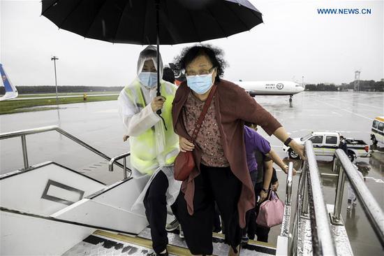 A staff member holds an umbrella for a passenger boarding a plane amid a downpour at Shenyang Taoxian International Airport in Shenyang, northeast China's Liaoning Province, Aug. 27, 2020. Typhoon Bavi, the eighth of this year, brought gales and rainstorms to cities in northeast China. (Photo by Chen Song/Xinhua)
