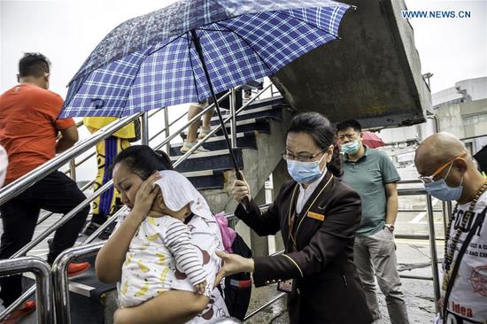 A staff member holds an umbrella for passengers boarding a plane amid a downpour at Shenyang Taoxian International Airport in Shenyang, northeast China's Liaoning Province, Aug. 27, 2020. Typhoon Bavi, the eighth of this year, brought gales and rainstorms to cities in northeast China. (Photo by Chen Song/Xinhua)