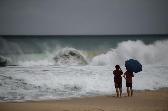 Two men watch the high waves brought by Typhoon Maysak on Haeundae beach in Busan on Wednesday.