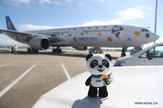 Photo taken on Sept. 19, 2020 shows a doll of the mascot of China International Import Expo (CIIE) and a flight featuring the mascot at the Guangzhou Baiyun International Airport in Guangzhou, south China's Guangdong Province. The CIIE-themed airplane of China Southern Airlines made its debut here and made its maiden flight from Guangzhou to Shanghai on Saturday. (Xinhua) 