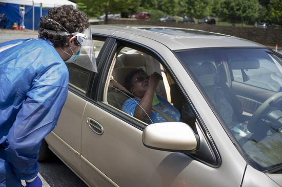 A medical worker instructs a woman to take a swab sample at a COVID-19 drive-thru testing site in Atlanta, Georgia, the United States, July 20, 2020. (Photo by Alan Chin/Xinhua)