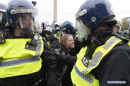 Police officers detain a protester during an anti-coronavirus restrictions protest in Trafalgar Square in London, Britain, on Sept. 26, 2020. Police has shut down an anti-coronavirus restrictions protest in central London on Saturday because crowds have not complied with social distancing rules. At least three protesters and one police officer were reportedly injured and treated by medical staff after they clashed at the anti-lockdown protest in Trafalgar Square. (Photo by Ray Tang/Xinhua)