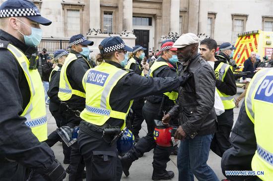 Police officers detain a protester during an anti-coronavirus restrictions protest in Trafalgar Square in London, Britain, on Sept. 26, 2020. Police has shut down an anti-coronavirus restrictions protest in central London on Saturday because crowds have not complied with social distancing rules. At least three protesters and one police officer were reportedly injured and treated by medical staff after they clashed at the anti-lockdown protest in Trafalgar Square. (Photo by Ray Tang/Xinhua)