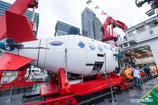 A journalist works next to the manned submersible Jiaolong on its mothership Shenhai Yihao (DeepSea No. 1) at a port in Shenzhen, south China's Guangdong Province, Oct. 13, 2020. The manned submersible Jiaolong, its mothership Shenhai Yihao (DeepSea No. 1), and dredging vessel Tian Kun Hao will be displayed during the China Marine Economy Expo (CMEE). (Xinhua/Mao Siqian)