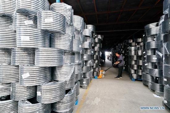 A staff member moves bicycle rims at the Tangshan Jinhengtong Group in Lutai Economic Development Zone of Tangshan City, north China's Hebei Province, Oct. 14, 2020. In recent years, local authorities of Lutai Economic Development Zone in Tangshan have pushed forward the upgrading and industrial agglomeration of local bicycle components production companies. With more than 40 companies achieving a yearly revenue of about 5 billion yuan (about 745 million U.S. dollars), the bicycle component products have made their presence in both domestic and overseas market. (Xinhua/Mu Yu)