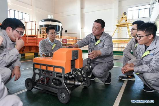 Qiao Sukai (C) discusses with his team members on an underwater robot at a training center in Shenzhen, south China's Guangdong Province, Nov. 20, 2019. Every 18 months, the Dayawan Nuclear Power Plant has to undergo a fuel assemblies replacement, which is one of the most important moments for the nuclear power plant. Dozens of engineers are divided into four shifts and operate the equipment day and night when the reactor is shut down. Their leader, Qiao Sukai, has been dealing with nuclear fuel since July 1993 when the nuclear fuel assembly of Dayawan Nuclear Power Plant arrived. The professional and technical maintenance team led by Qiao is responsible for the maintenance of nuclear fuel for more than half of the nuclear power units in the country. Qiao and his team have successfully operated fuel installing and uninstalling more than 170 times without making a single mistake. (Xinhua/Mao Siqian)