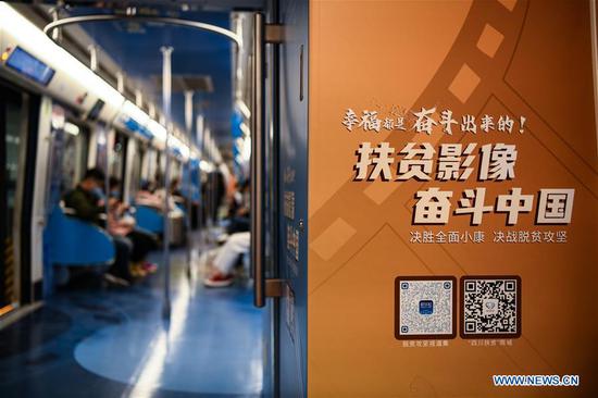 Passengers take a poverty-alleviation-themed train of the Line 1 of Chengdu Metro in Chengdu, southwest China's Sichuan Province, Oct. 17, 2020. China marked the seventh National Poverty Relief Day on Saturday. A poverty-alleviation-themed train, with photos and videos displaying poverty alleviation achievements in Sichuan, made its first running on the Line 1 of Chengdu Metro on Saturday. The train will run till the end of this year. (Xinhua/Wang Xi)