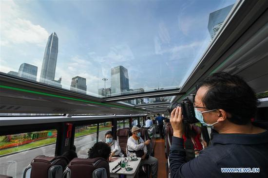 A journalist takes photos in a sightseeing bus in Shenzhen, south China's Guangdong Province, Oct. 22, 2020. Shenzhen on Thursday launched three sightseeing bus lines for tourists, which respectively showcase the culture, technology and night view of the city. (Xinhua/Mao Siqian)