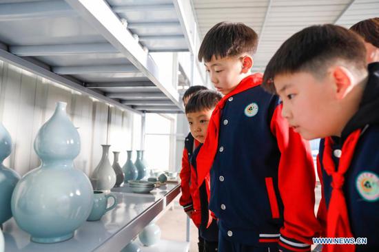 Primary school students view porcelain works at a workshop of Ru porcelain in Baofeng County, central China's Henan Province, on Nov. 15, 2020. Baofeng County is famous for producing Ru porcelain, one of the five famous porcelains during the Song Dynasty (960-1279) in ancient China. More than 90 students of Xichengmen Primary School in Baofeng County took part in a practical activity here on Sunday to learn about Ru porcelain. (Photo by He Wuchang/Xinhua)