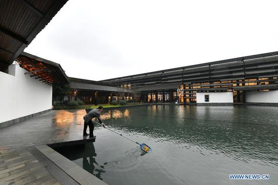 A staff member cleans a pond at the Wuzhen International Internet Exhibition and Convention Center in Wuzhen, east China's Zhejiang Province, Nov. 22, 2020. The World Internet Conference will be held here from Nov. 23 to 24, with the theme of 