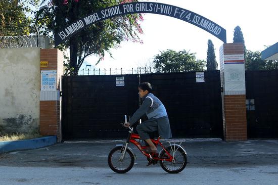 A boy rides past a closed school in Islamabad, Pakistan on Nov. 26, 2020. Pakistan closed educational institutions till Jan. 10 next year following rises in the cases of COVID-19. (Xinhua/Ahmad Kamal)