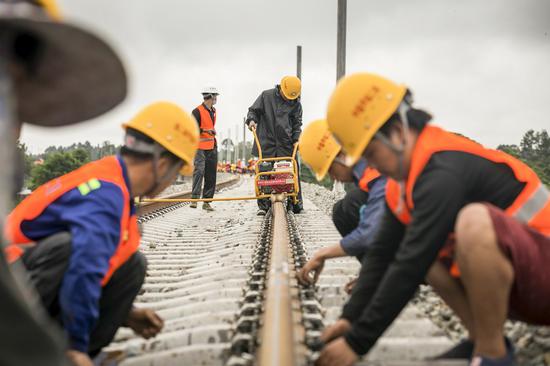 Workers install seamless welded rails on the China-Laos railway in the northern suburbs of Vientiane, Laos, June 18, 2020. (Photo by Kaikeo Saiyasane/Xinhua)