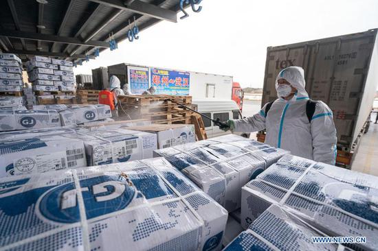 A staff member sprays disinfectant on the package of imported cold chain food at a regional cold chain center in Wuhan, capital of central China's Hubei Province, Jan. 7, 2021. (Xinhua/Xiong Qi)