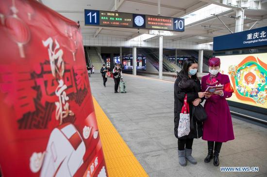 A staff member distributes epidemic prevention leaflets to a passenger at Chongqingbei Railway Station in Chongqing, southwest China, Jan. 25, 2021. The prevention and control efforts against the COVID-19 epidemic are strengthened at railway stations in Chongqing to protect the safety of passengers. (Xinhua/Huang Wei)