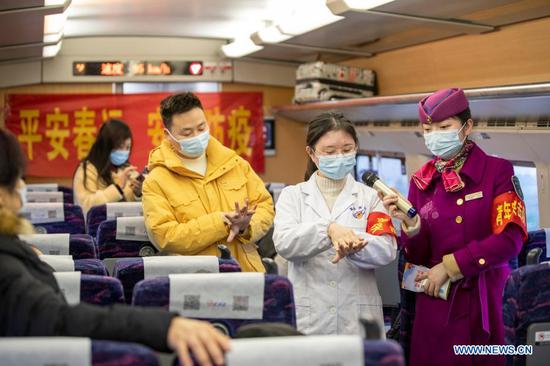 A medical worker shows the passengers how to wash hands in seven steps on a train on Jan. 25, 2021. The prevention and control efforts against the COVID-19 epidemic are strengthened at railway stations in Chongqing to protect the safety of passengers. (Xinhua/Huang Wei)