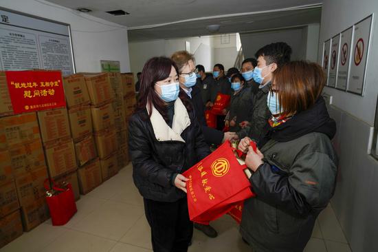 Staff members from the federation of trade unions of Jiulongpo District of Chongqing distribute Spring Festival gift packs to employees who choose to stay put during the Spring Festival holiday at a company in Chongqing, southwest China, Jan. 28, 2021. (Xinhua/Liu Chan)