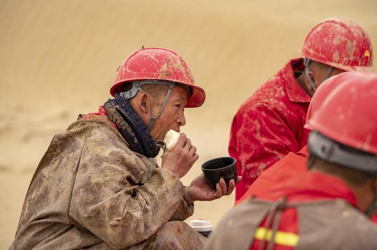 Workers of the geophysical survey team have lunch in the Taklimakan Desert, northwest China's Xinjiang Uygur Autonomous Region, Feb. 25, 2021. (Xinhua/Hu Huhu)