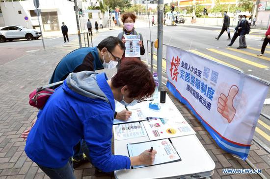 Citizens sign their names during a campaign in support of the decision on improving the electoral system of the Hong Kong Special Administrative Region by the National People's Congress (NPC) in Hong Kong, south China, March 11, 2021. The decision was passed by an overwhelming majority vote at the fourth session of the 13th NPC, China's top legislature, on Thursday. (Xinhua/Lo Ping Fai)