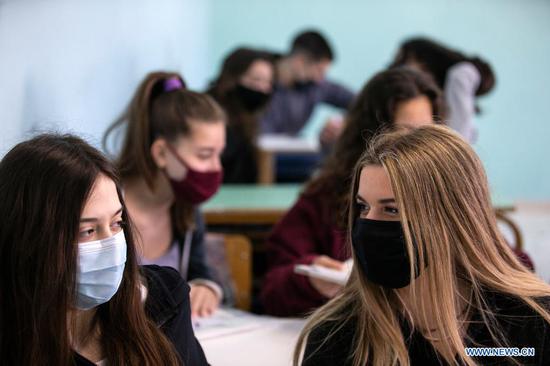 Students wearing face masks are seen in their classroom at a high school in Glyfada, a southern suburb of Athens, Greece, on April 12, 2021. In Greece, high school students returned to classrooms nationwide on Monday after five months of remote learning, although the nationwide lockdown, which started on Nov. 7, 2020, is still in force. (Xinhua/Marios Lolos)