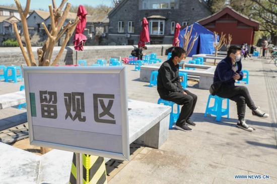 People stay at an observation area after receiving COVID-19 vaccines on a mobile vaccination vehicle outside the Donghua Gate of the Palace Museum in Beijing, capital of China, April 13, 2021. The bus-like facilities, equipped with vaccination stations, medical refrigerators and first-aid equipment, have been rolled out in different districts of Beijing to save time and improve inoculation efficiency. (Xinhua/Zhang Yuwei)