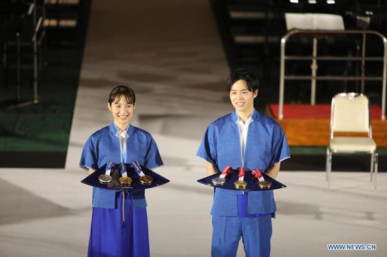 Models present the medal trays during an unveiling event of the items that will be used for the victory ceremonies of the Tokyo 2020 Olympic and Paralympic Games at Ariake Arena in Tokyo, Japan on June 3, 2021. (Xinhua/Wang Zijiang)