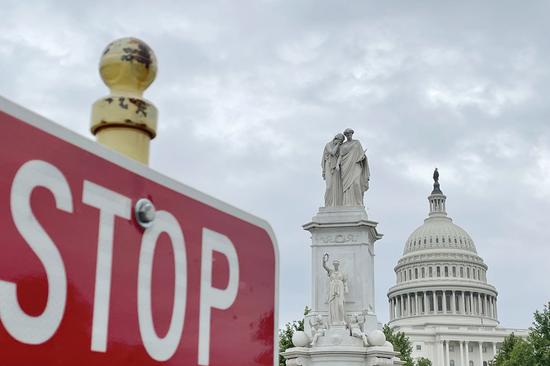 Photo taken on May 28, 2021 shows the U.S. Capitol building behind a traffic sign in Washington, D.C., the United States. (Xinhua/Liu Jie)