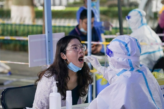 A medical worker takes a swab sample from a woman for nucleic acid test at a testing spot in Nanjing, capital of east China's Jiangsu Province, July 29, 2021. (Xinhua/Li Bo)