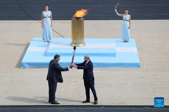 Special representative and Vice-President of Beijing 2022 Yu Zaiqing (R) receives the torch with the Olympic Flame from President of the Hellenic Olympic Committee Spyros Capralos during the handover ceremony of the Olympic Flame for the Beijing 2022 Winter Olympic Games at the Panathenaic Stadium in Athens, Greece, Oct. 19, 2021. (Xinhua/Zheng Huansong)