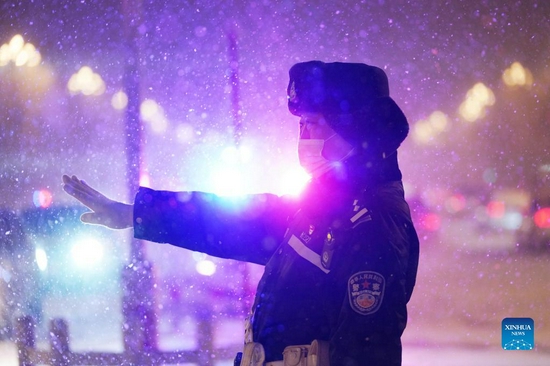 A police officer directs traffic in the snow in Harbin City, northeast China's Heilongjiang Province, Nov. 22, 2021. Heavy snowfall hit many parts of Heilongjiang recently. Staff members of various sectors are braving frigid gusts and snowflakes to ensure normal availability of essential public services. (Xinhua/Wang Jianwei) 