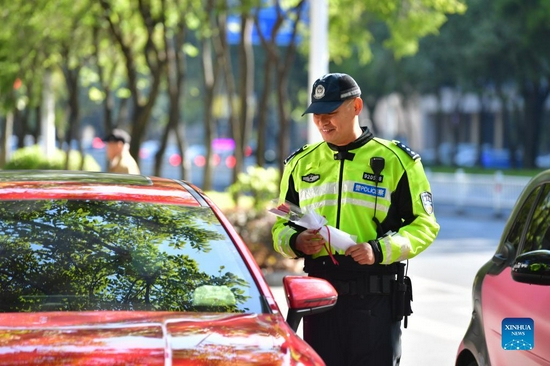 A traffic police officer sends flowers to a driver who stops politely to allow pedestrians to cross in Liuzhou, south China's Guangxi Zhuang Autonomous Region, Dec. 2, 2021. Dec. 2 marks the national traffic safety day in China. An event was held in Liuzhou to promote traffic safety. (Xinhua/Huang Xiaobang) 