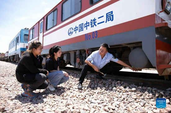 Sida Phengphongsawanh (C) learns to inspect a train from a Chinese instructor at the China Railway No. 2 Engineering Group (CREC-2) railing base for the China-Laos railway, on the northern outskirts of Vientiane, capital of Laos, Sept. 12, 2021. Sida Phengphongsawanh, 22, is a trainee for China-Laos railway train driver. The China-Laos Railway, which connects Kunming in China's Yunnan Province with Lao capital Vientiane, is the first railway project built with Chinese investment, jointly operated by China and Laos and directly connected to China's railway network. While building the railway, the Laos-China Railway Co., Ltd. has opened training course for around 600 Lao trainees to learn train driving, scheduling and maintenance. Sida is one of them. 
